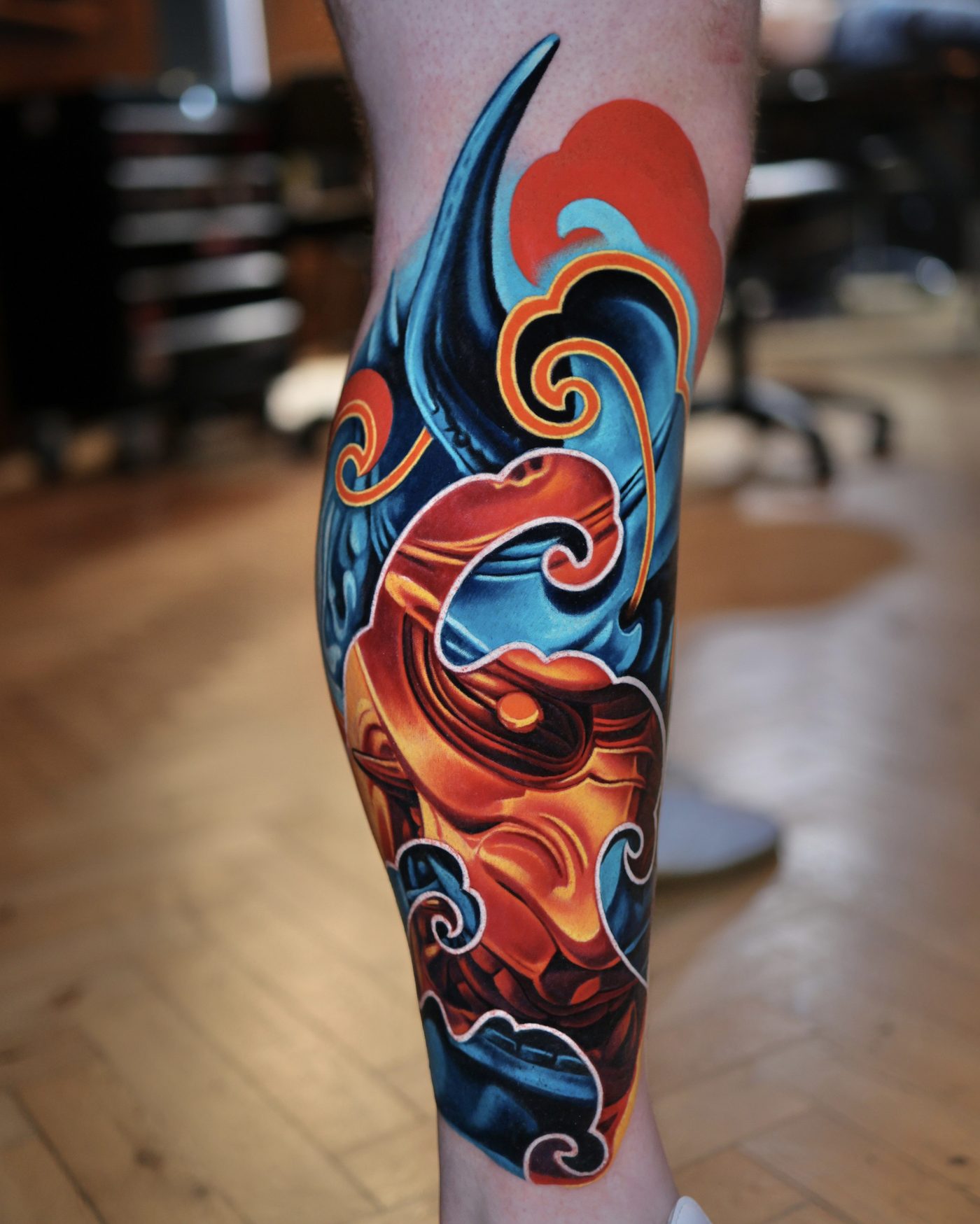 Modern Japanese hannya mask lower leg in blue and orange, tattooed by Volkan Demirci in London